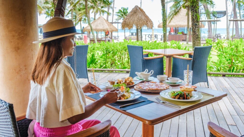 Woman having breakfast table on the beach of Koh Kood in Thailand, breakfast table at a luxury hotel.